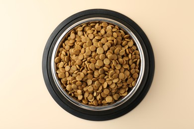 Photo of Dry pet food in feeding bowl on beige background, top view