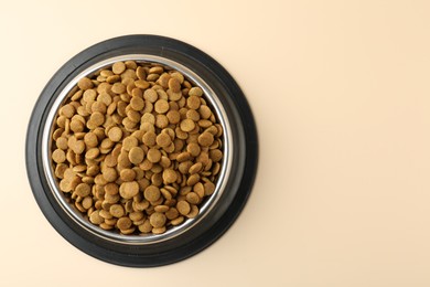 Photo of Dry pet food in feeding bowl on beige background, top view. Space for text