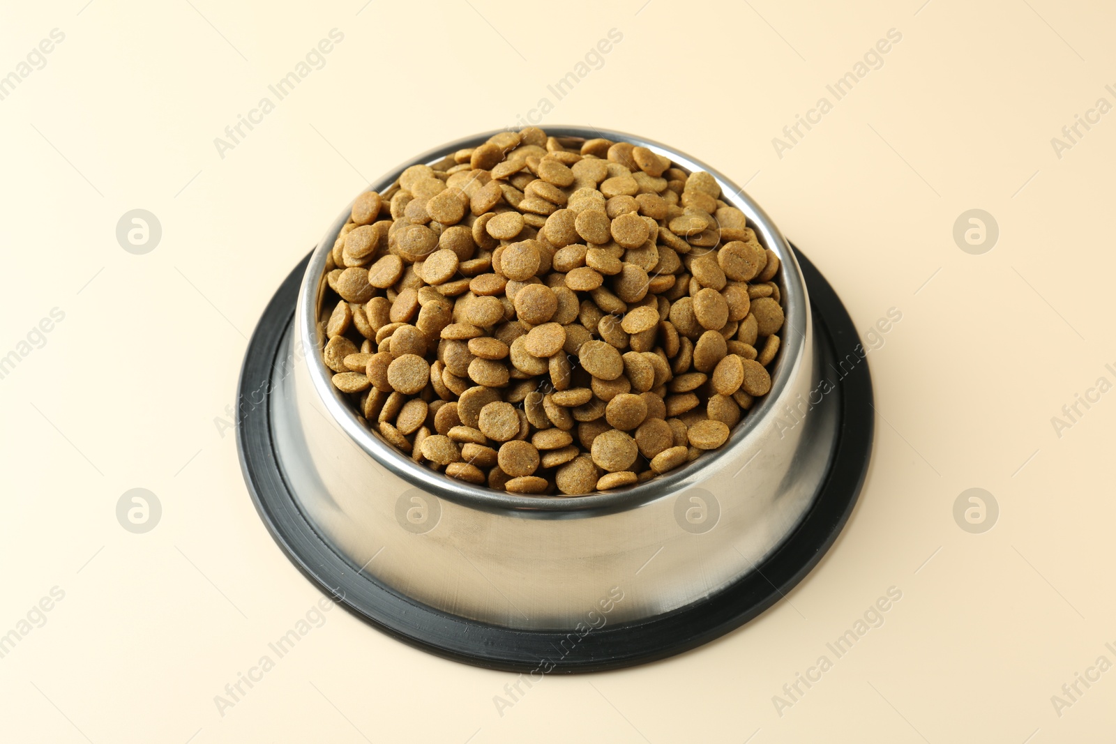 Photo of Dry pet food in feeding bowl on beige background