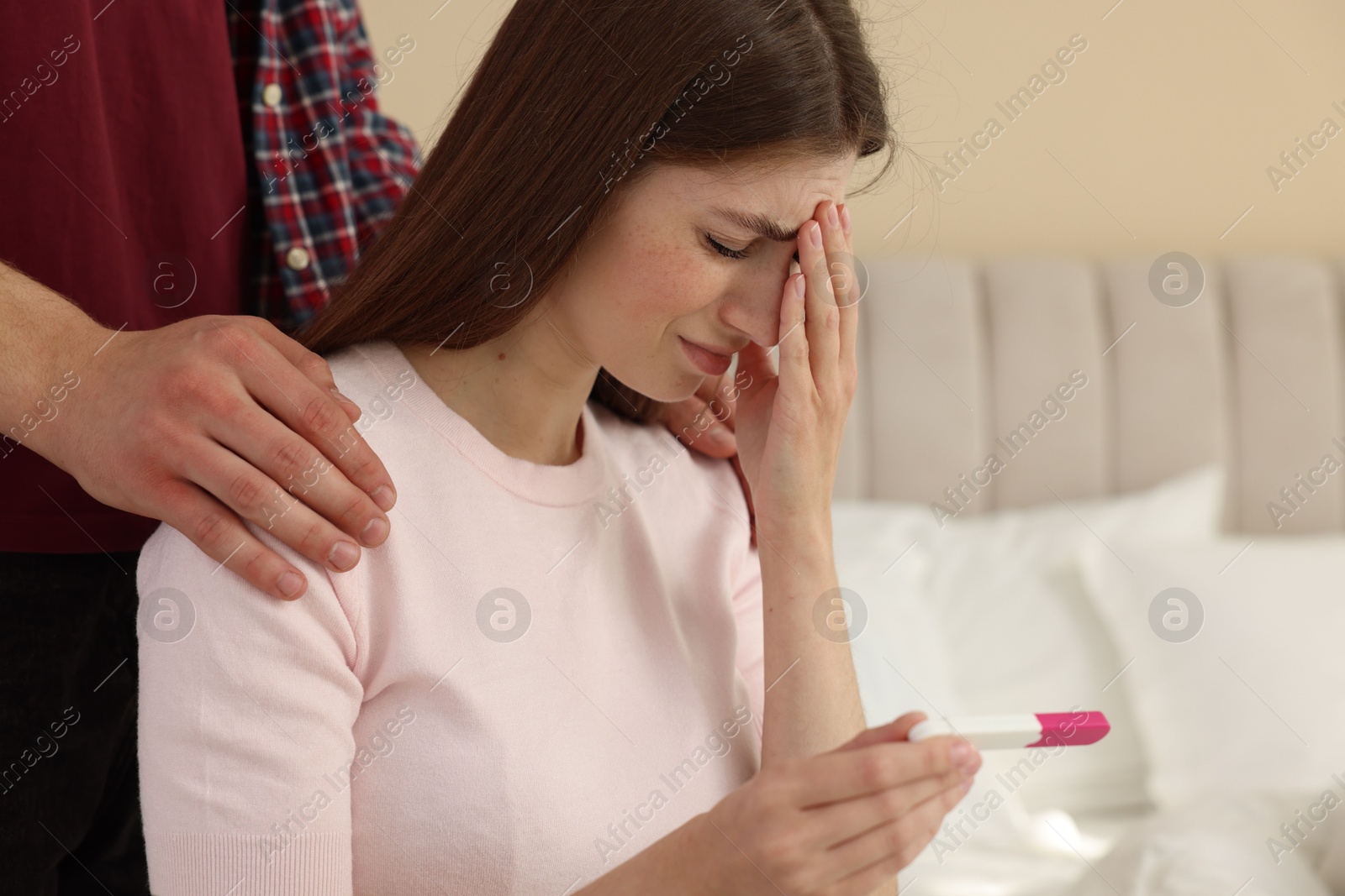 Photo of Upset woman with negative pregnancy test indoors. Man supporting his wife at home