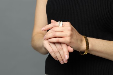 Photo of Woman wearing stylish ring and golden bracelet on grey background, closeup