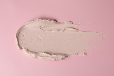 Cream on pink background, top view. Sample of cosmetic product