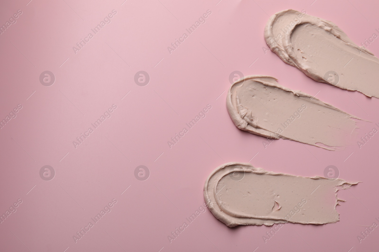 Photo of Cream on pink background, top view and space for text. Samples of cosmetic product