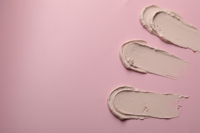 Photo of Cream on pink background, top view and space for text. Samples of cosmetic product