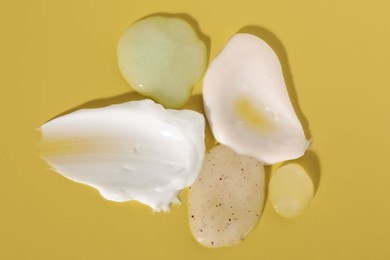 Photo of Samples of cosmetic products on yellow background, flat lay