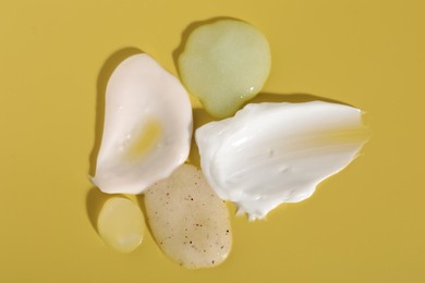 Photo of Samples of different cosmetic products on yellow background, flat lay