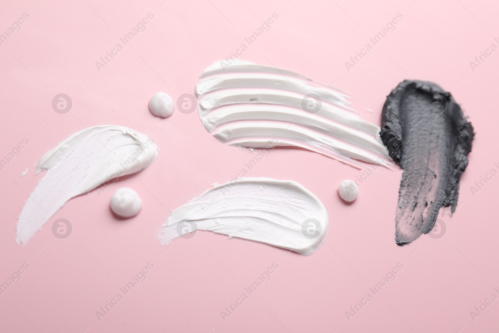 Photo of Samples of different cosmetic products on pink background, flat lay