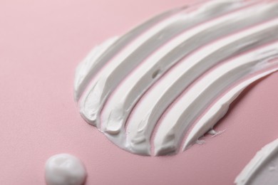 Photo of Cream on pink background, closeup. Sample of cosmetic product