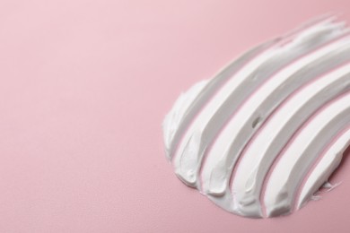 Photo of Cream on pink background, closeup. Sample of cosmetic product