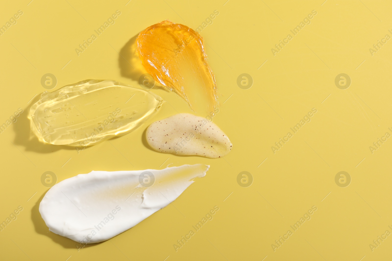 Photo of Samples of different cosmetic products on yellow background, above view. Space for text