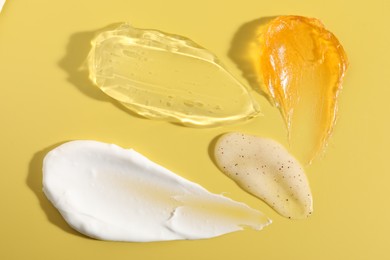 Photo of Samples of different cosmetic products on yellow background, above view