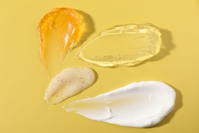 Photo of Samples of different cosmetic products on yellow background, above view