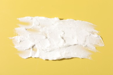 Cream on yellow background, closeup. Sample of cosmetic product