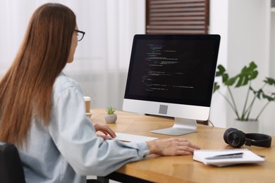 Photo of Programmer working on computer at wooden desk indoors