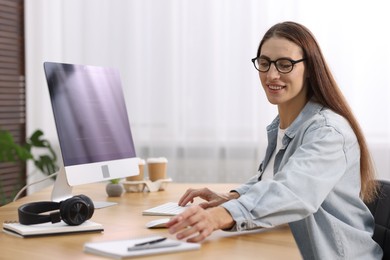 Photo of Programmer working on computer at wooden desk indoors