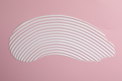 Photo of Cream on pink background, top view. Sample of cosmetic product