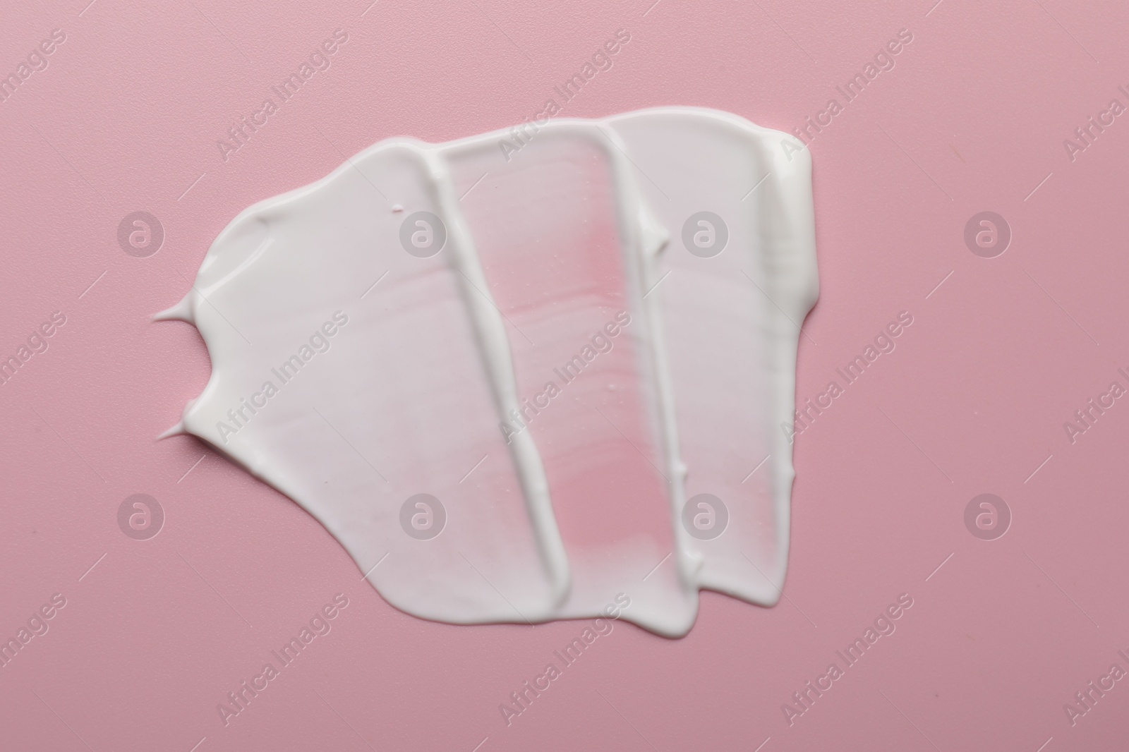 Photo of Cream on pink background, top view. Sample of cosmetic product