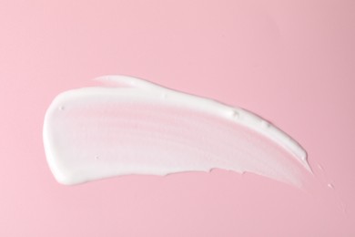 Photo of Cream on pink background, top view. Sample of cosmetic product