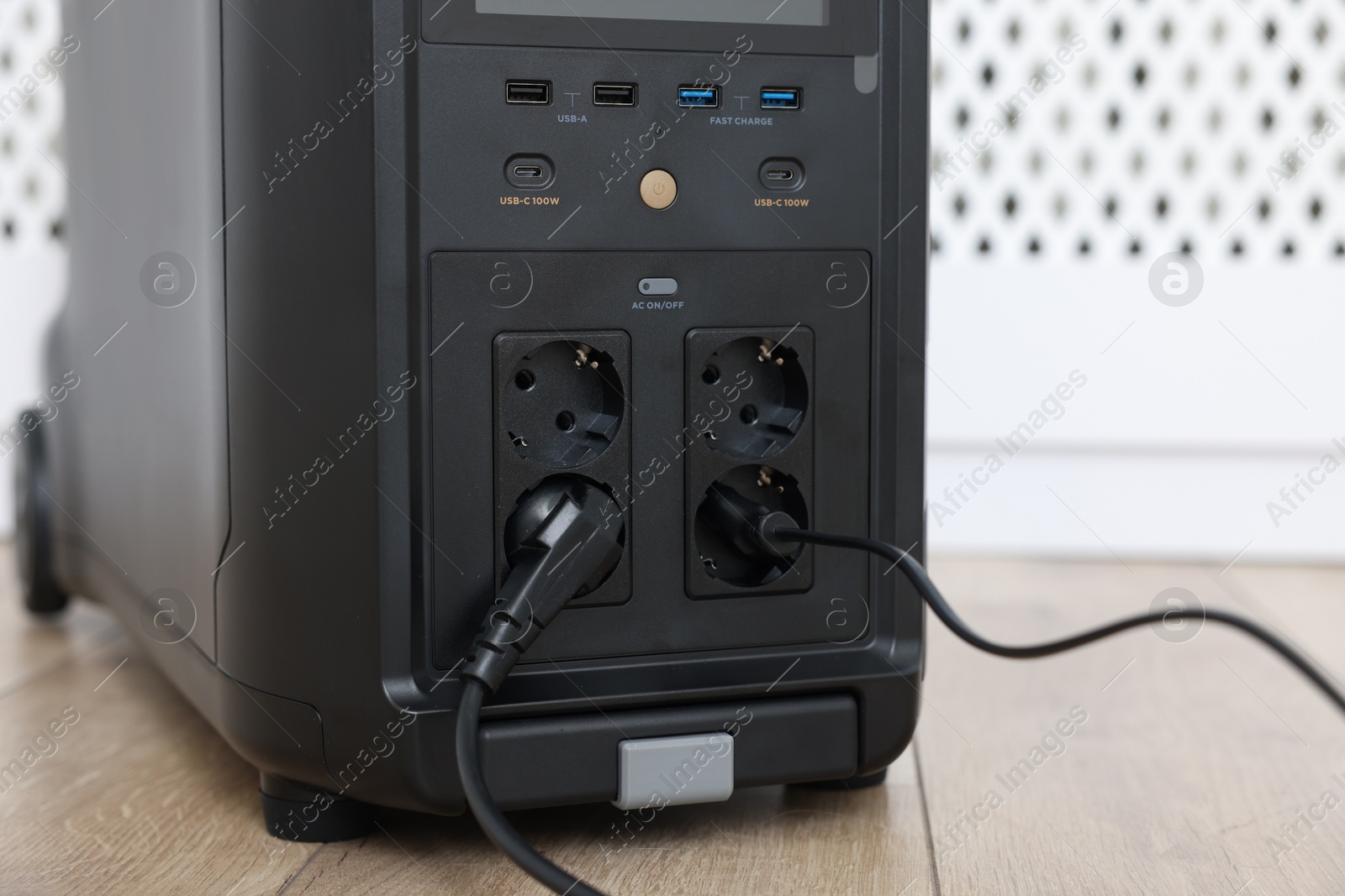 Photo of Modern portable power station on floor indoors, closeup