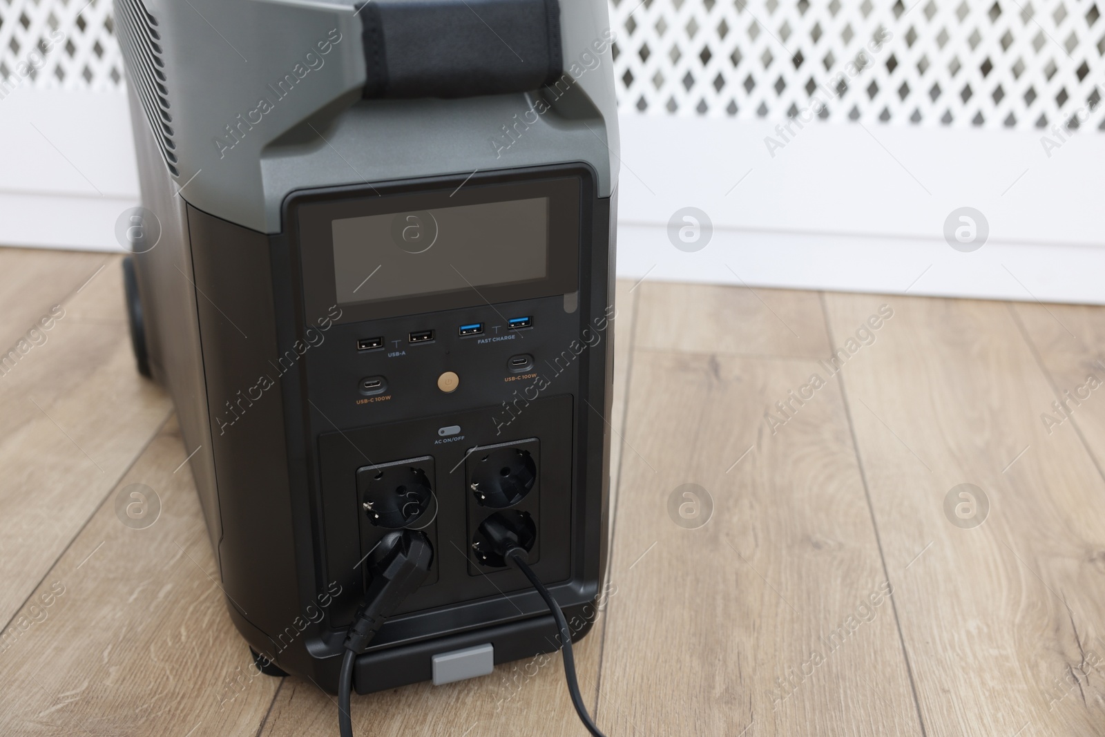 Photo of Modern portable power station on floor indoors, closeup. Space for text