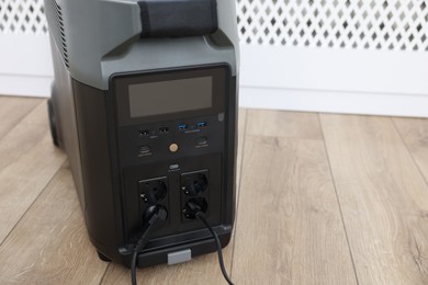 Photo of Modern portable power station on floor indoors, closeup. Space for text