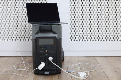 Photo of Modern portable power station, charging attached devices indoors, space for text