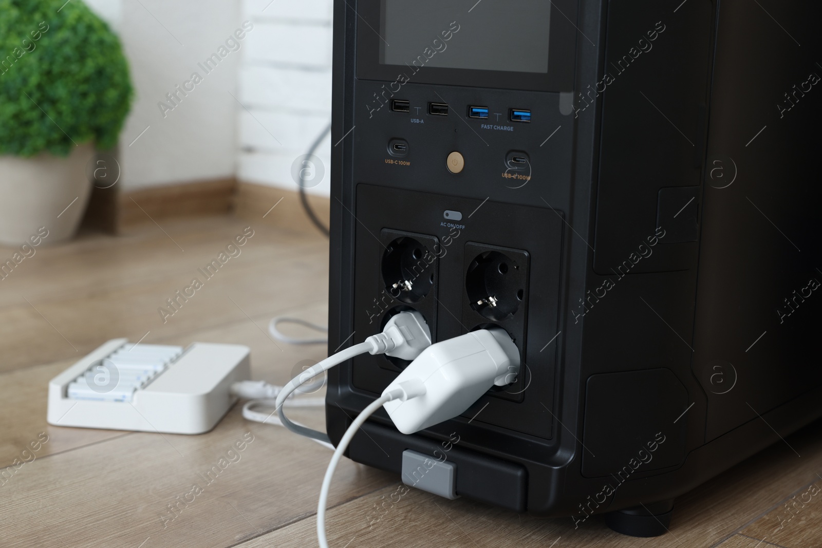 Photo of Modern portable power station with attached device indoors, closeup