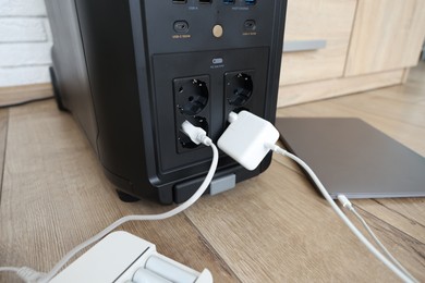 Photo of Modern portable power station, charging attached devices indoors, closeup