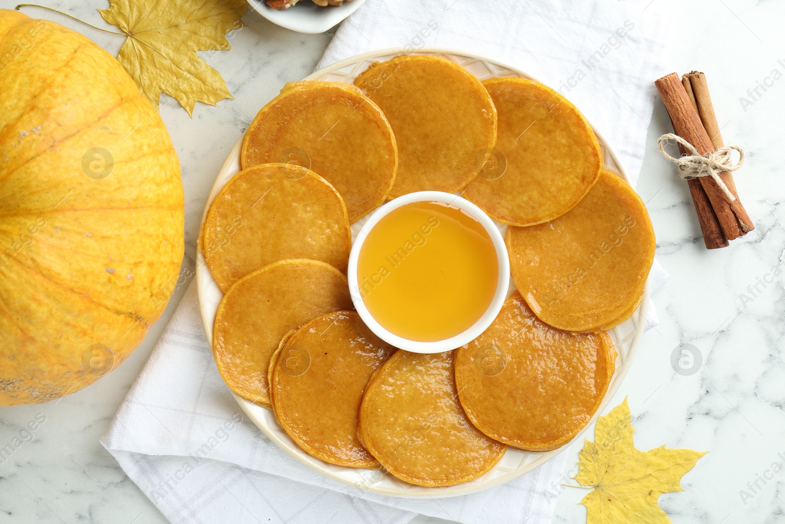 Photo of Tasty pumpkin pancakes served on white marble table, flat lay