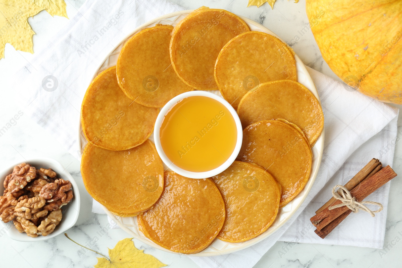 Photo of Tasty pumpkin pancakes served on white marble table, flat lay