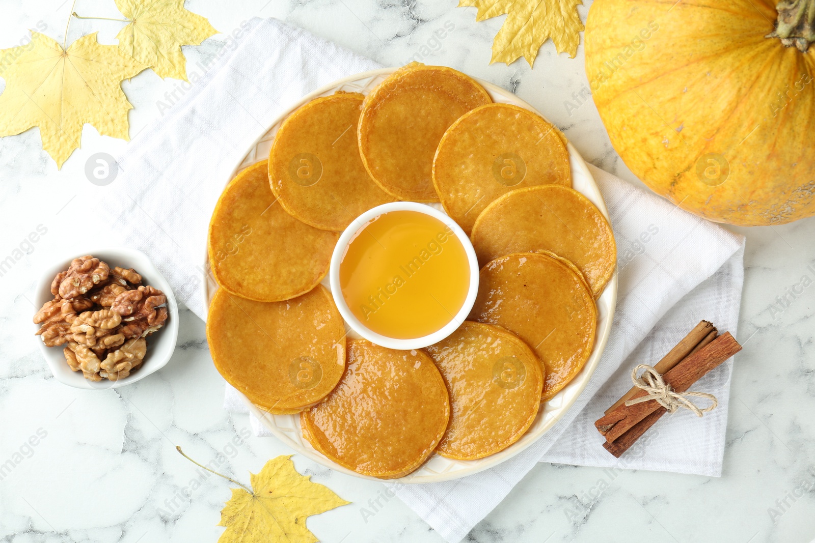 Photo of Tasty pumpkin pancakes served on white marble table, flat lay