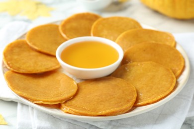 Photo of Tasty pumpkin pancakes with honey on white table, closeup