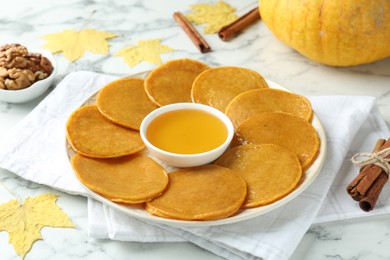 Photo of Tasty pumpkin pancakes on white marble table, closeup