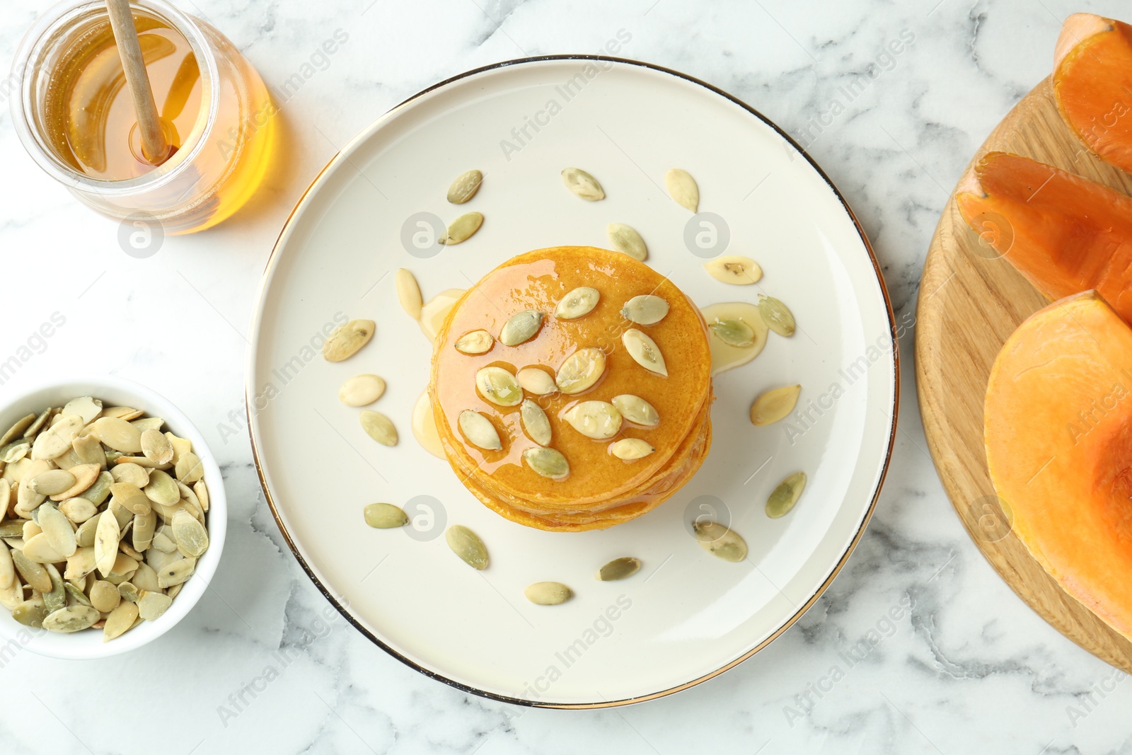 Photo of Tasty pumpkin pancakes served on white marble table, flat lay