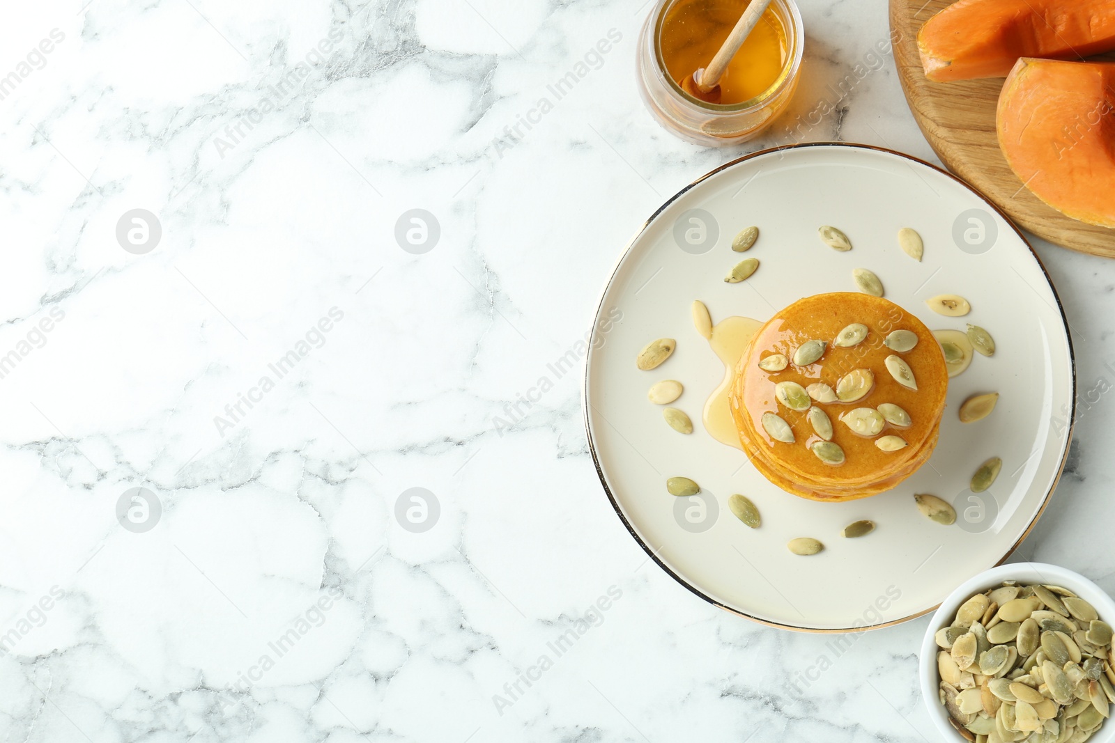 Photo of Tasty pumpkin pancakes served on white marble table, flat lay. Space for text