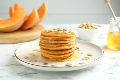 Photo of Tasty pumpkin pancakes with seeds on white marble table, closeup