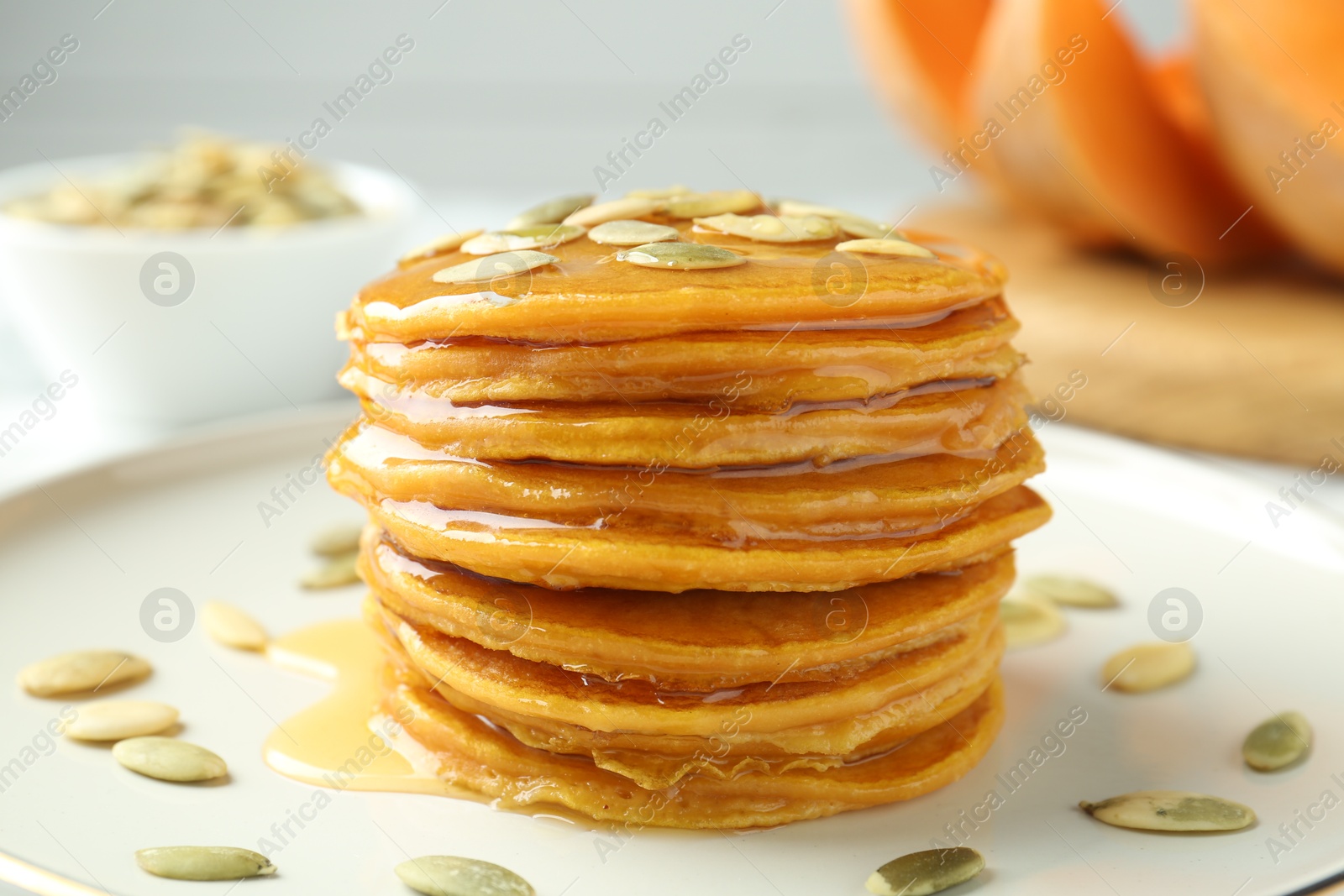 Photo of Tasty pumpkin pancakes with seeds on table, closeup