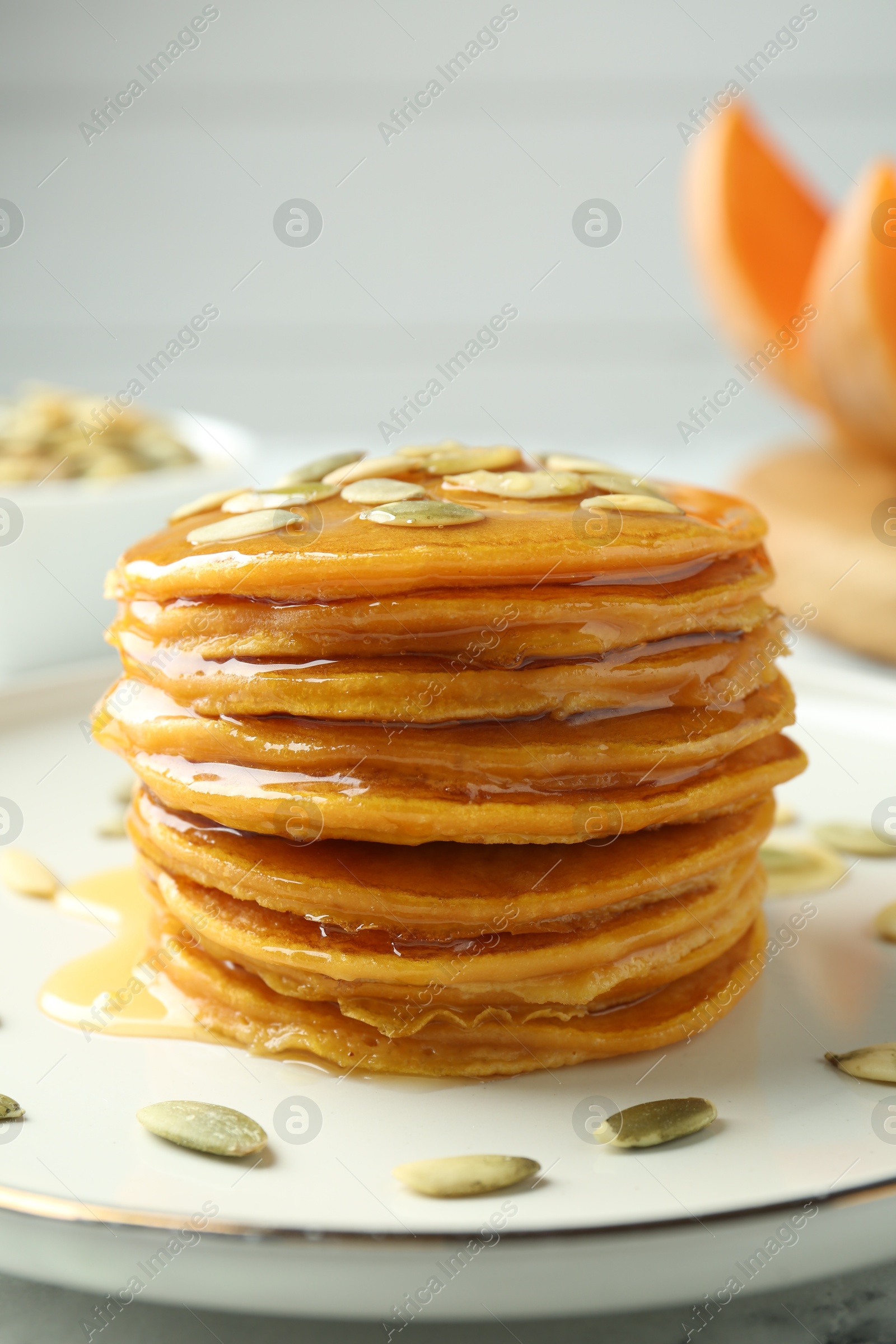 Photo of Tasty pumpkin pancakes with seeds on table, closeup