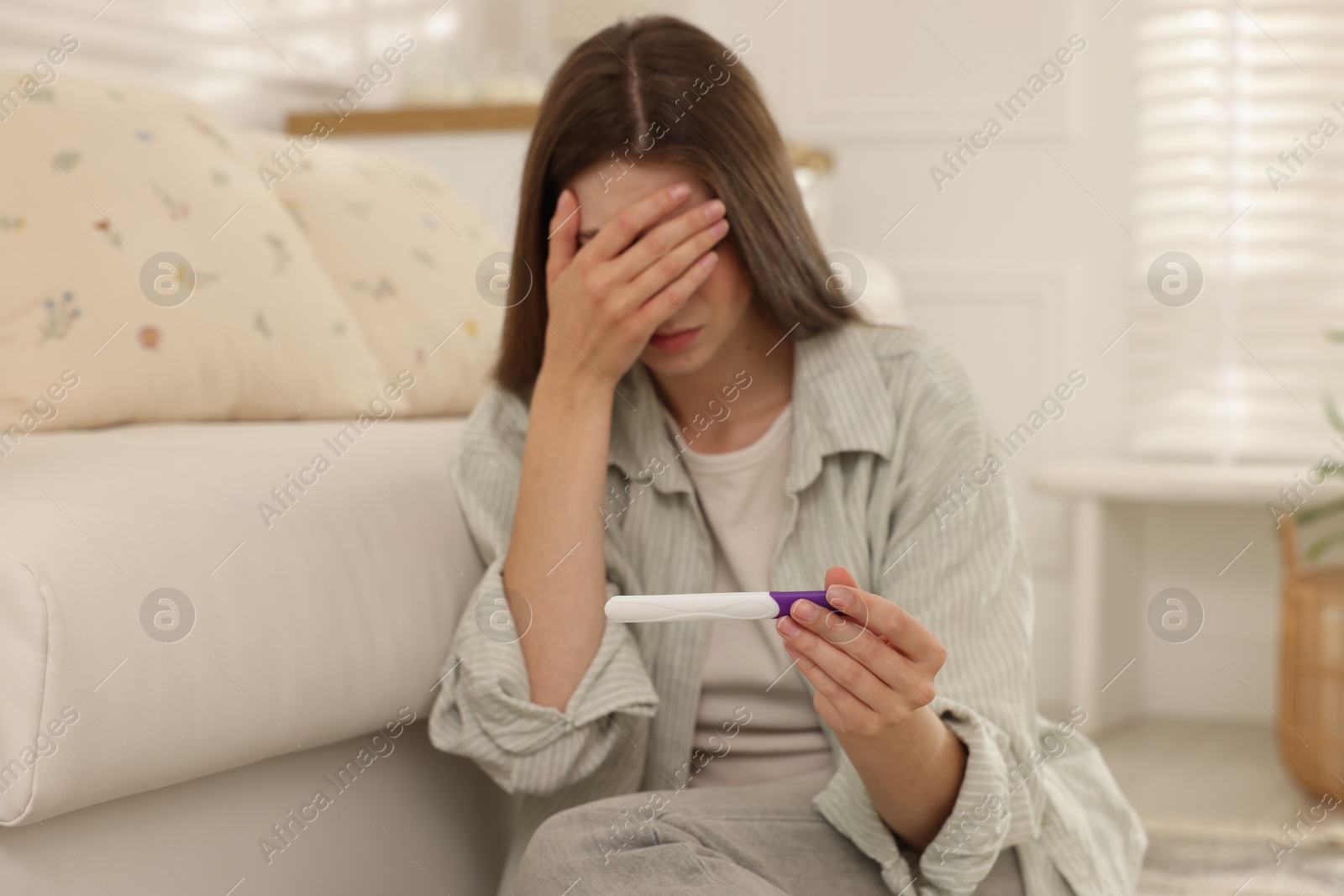 Photo of Upset woman with negative pregnancy test at home