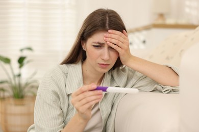 Photo of Upset woman with negative pregnancy test at home