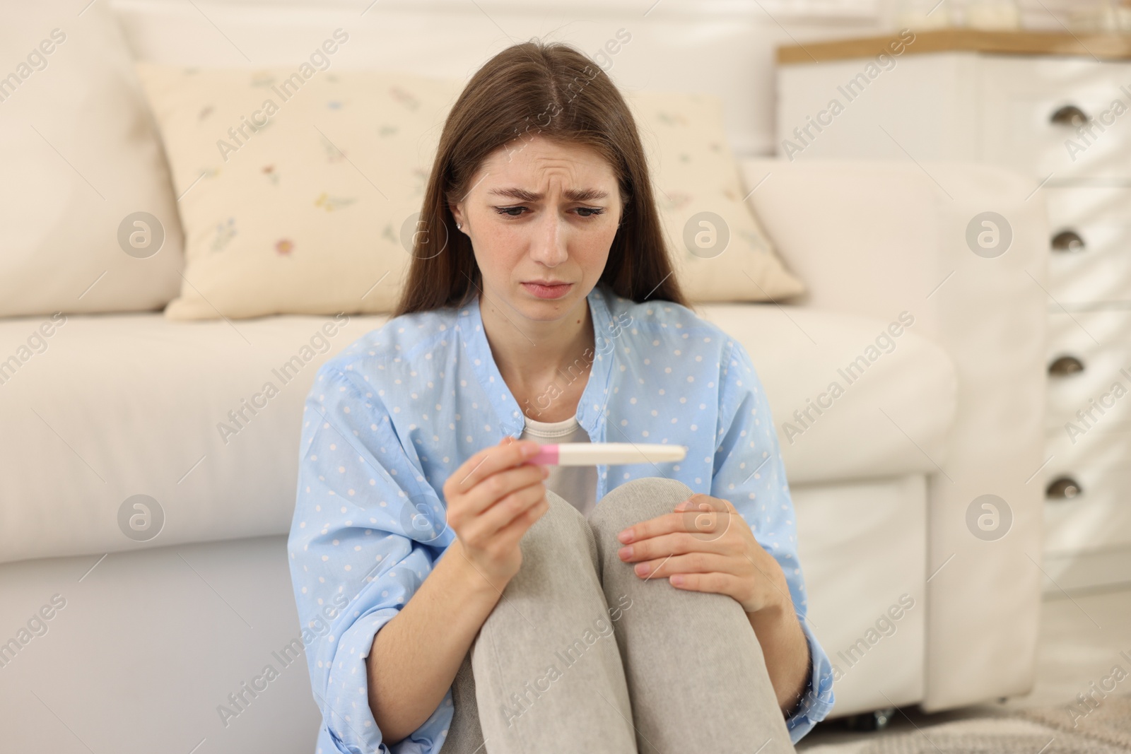 Photo of Upset woman with negative pregnancy test at home