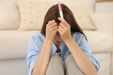 Photo of Upset woman with negative pregnancy test at home