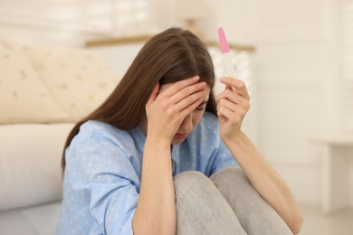 Photo of Upset woman with negative pregnancy test at home