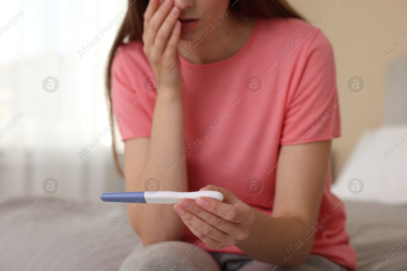 Photo of Woman with negative pregnancy test on bed at home, closeup