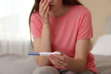 Photo of Woman with negative pregnancy test on bed at home, closeup