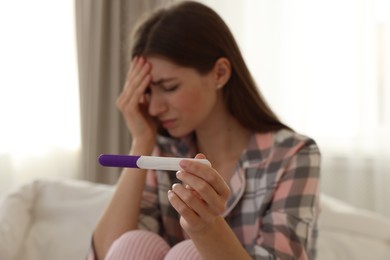 Photo of Woman with negative pregnancy test at home, selective focus