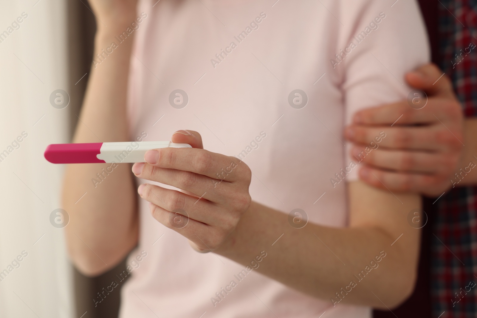 Photo of Woman with negative pregnancy test indoors, closeup. Man supporting his wife at home