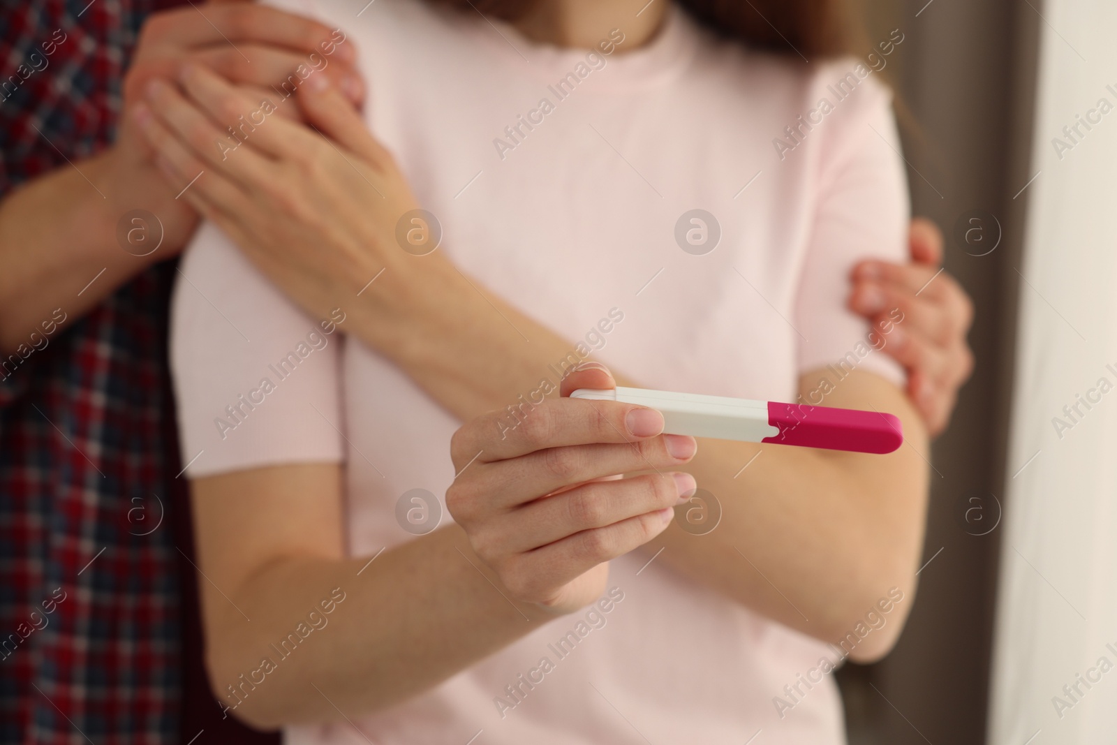 Photo of Woman with negative pregnancy test indoors, closeup. Man supporting his wife at home