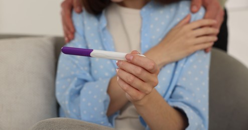 Photo of Woman with negative pregnancy test indoors, closeup. Man supporting his wife at home