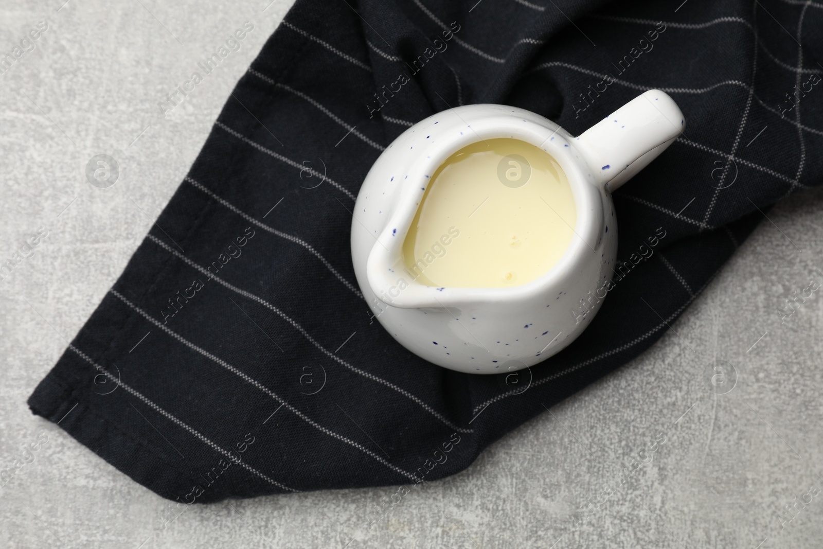 Photo of Condensed milk in jug on light grey table, top view